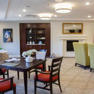 A cozy living room with modern furniture, featuring a table and chairs, a fireplace, and artwork on the wall.