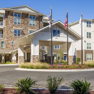 A modern apartment complex with a landscaped entrance and multiple flagpoles.
