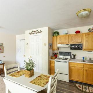 A cozy kitchen and dining area with wooden cabinets, a white stove, and a small table set for two.