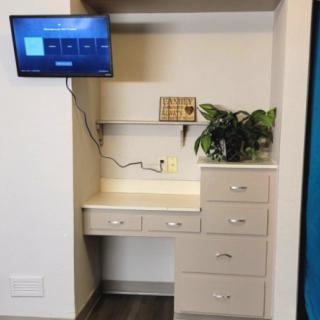 A small office setup with a desk, drawers, and a mounted television.