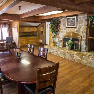 A cozy rustic dining room with a wooden table, chairs, and a stone fireplace.