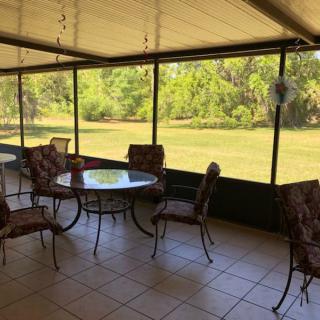 A screened patio with a table and chairs overlooking a green backyard.