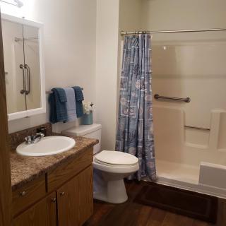 A clean and organized bathroom with a shower, toilet, sink, and storage cabinet.
