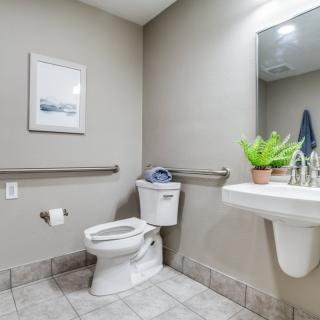 A clean bathroom with accessibility features including handrails and a tiled floor.