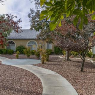A suburban house with a curved pathway leading through a landscaped front yard.