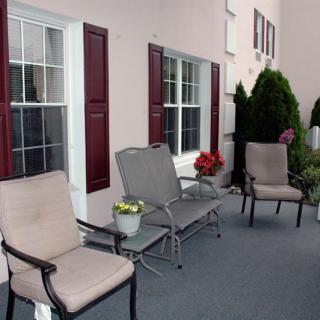 A cozy outdoor patio area with chairs and decorative plants.