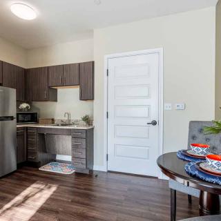 A modern apartment kitchen with stainless steel appliances and a neatly set dining table.