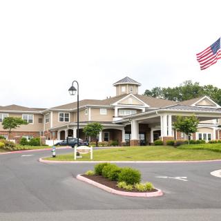 A hospital building with an American flag and a landscaped driveway.