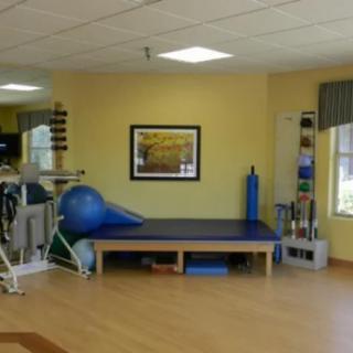 A physical therapy room equipped with various fitness tools and a treatment table.