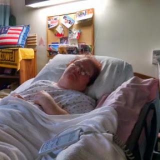 A patient resting in a hospital bed, surrounded by personal items.