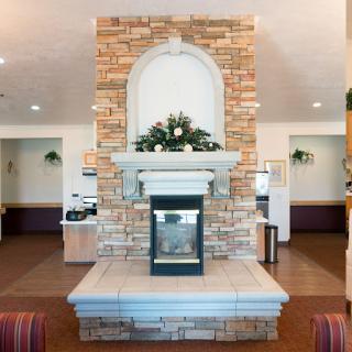 A cozy lobby featuring a decorative stone fireplace, enhanced with greenery.