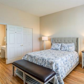 A well-furnished bedroom with a comfortable bed, two bedside lamps, and wooden flooring.