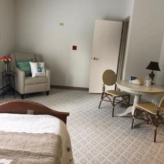 A cozy bedroom with a chair, table, and lamp.
