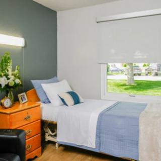 A cozy and neatly arranged bedroom with a single bed, decorated in minimalist style with soft colors.