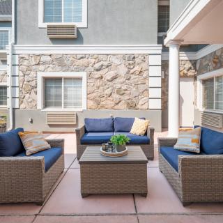 A modern outdoor patio with wicker furniture and blue cushions arranged around a central table.