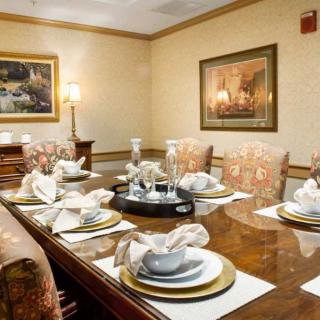 An elegant dining room with a formal table setting, featuring ornate chairs and decorative artwork on the walls.