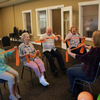 A group of seniors participating in a seated exercise session with resistance bands.