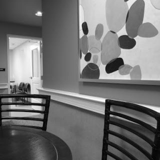 A minimalist interior scene featuring a table and chairs, complemented by abstract wall art.