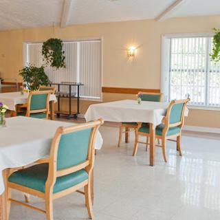 A spacious and inviting dining area featuring well-arranged tables and chairs, complemented by lush greenery.