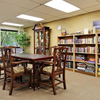 A cozy reading room with bookshelves, a large table, and chairs for studying.