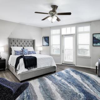 A modern bedroom with a large bed, stylish rug, and ample natural light.