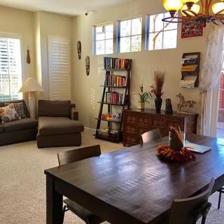 A cozy living and dining area with comfortable seating, bookshelves, and a decorative table.