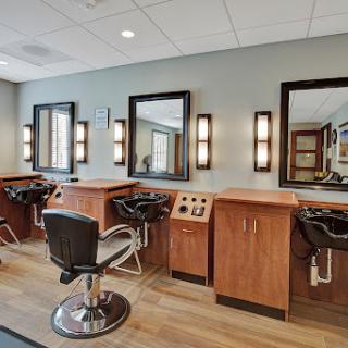 A modern hair salon featuring stylish chairs and well-lit mirrors.