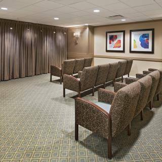 A small seating area with rows of upholstered chairs, carpeted floor, and framed artwork on the wall.