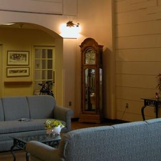 A cozy living room featuring a sofa set, a grandfather clock, and wall art.