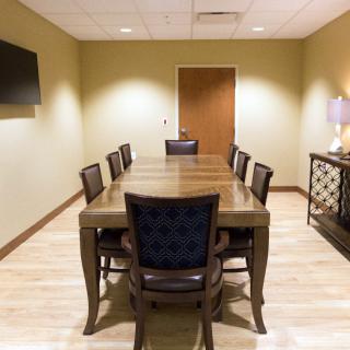 A well-appointed conference room with a large table and chairs, featuring modern decor and a wall-mounted television.