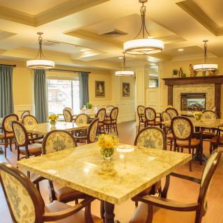 An elegant dining room featuring classic decor, chandeliers, and a cozy fireplace.