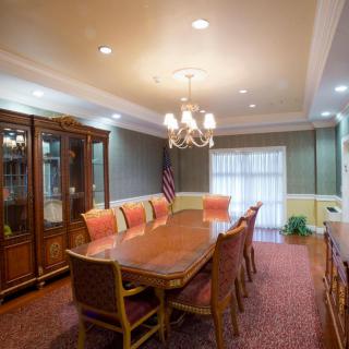 An elegant dining room with a chandelier, large wooden table, and upholstered chairs.