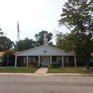A view of a community church with a flag and surrounding trees.