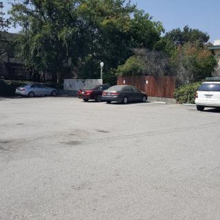 A quiet parking lot with several parked cars under a clear blue sky.
