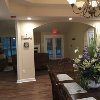 A cozy dining area with elegant decor, featuring a chandelier and floral centerpiece on a wooden table.
