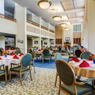 An elegant dining room with neatly arranged tables and chairs, featuring stylish lighting and place settings.