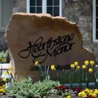 A decorative stone sign surrounded by flowers in front of a building.