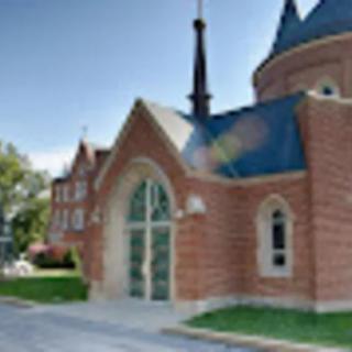 A brick church with a spire and arched windows under a clear sky.