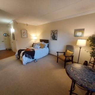 A cozy and well-decorated bedroom with a bed, chairs, lamps, and artwork on the walls.