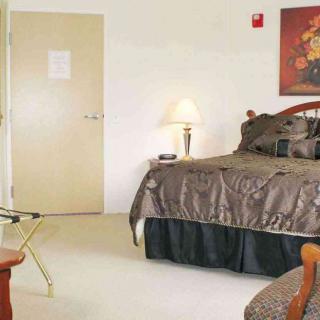 A cozy bedroom with a bed, lamp, and decorative painting on the wall.
