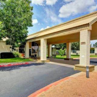 The entrance of a hotel with a covered driveway and surrounding greenery.