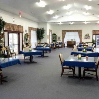 A spacious dining room with tables covered in blue tablecloths.