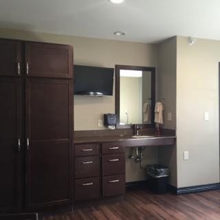 A modern interior featuring a wooden vanity with a mirror, storage cabinets, and a wall-mounted TV.