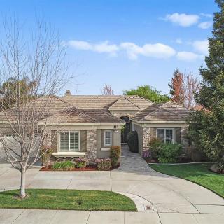 A suburban single-story house with a spacious driveway and landscaped front yard.