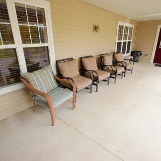 A row of chairs on a spacious porch, perfect for relaxing outdoors.