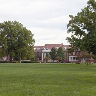 A scenic view of a university campus with lush green lawns and trees.