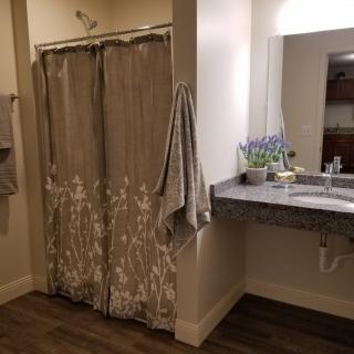 A cozy bathroom featuring a floral shower curtain, a sink with a mirror, and decorative touches like a potted plant.
