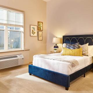 A modern bedroom with a plush blue bed and stylish decor.