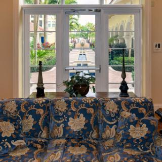 A beautifully decorated lobby area featuring a floral patterned sofa, with a view of the lush outdoor landscape through the glass doors.