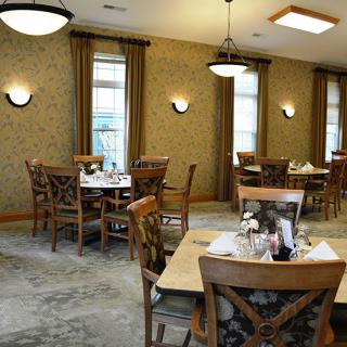 A cozy restaurant dining area with neatly arranged tables and chairs, complemented by warm lighting.